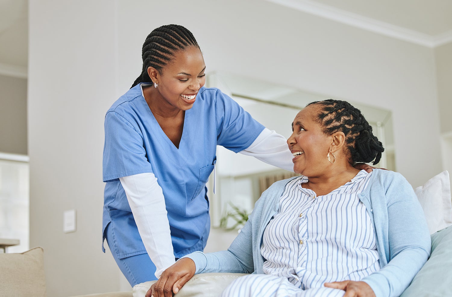 a caretaker laughing with a seated older woman