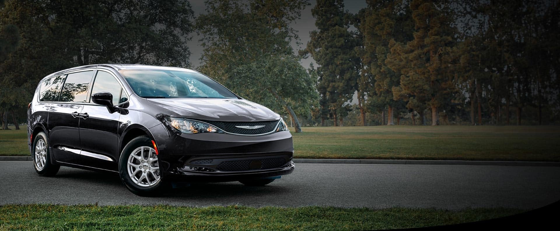 Black 2026 Chrysler Voyager LX parked in a park with trees behind it, a Chrysler Voyager for Bowie, TX families