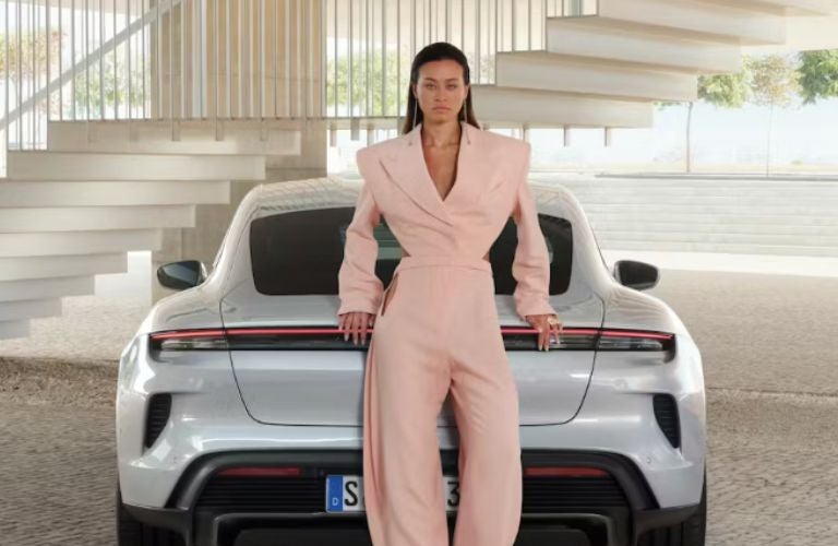 a woman standing at the rear of the 2025 Porsche Taycan 4S