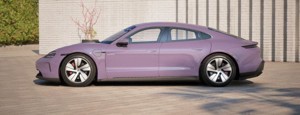 A profile view of a lavender electric sports car, resembling a Porsche, parked on a light-colored paved surface.