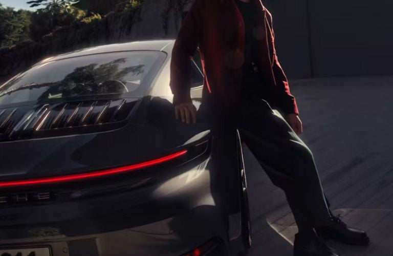 a man standing next to a Porsche