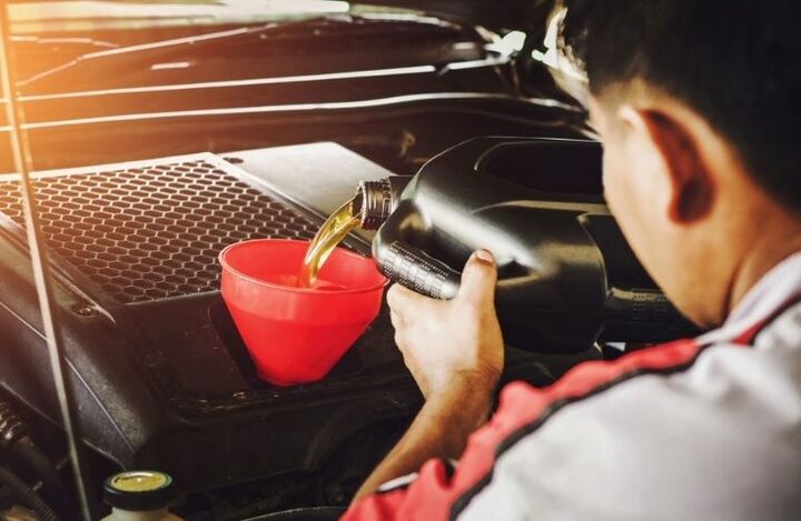Mechanic pouring oil to vehicle engine