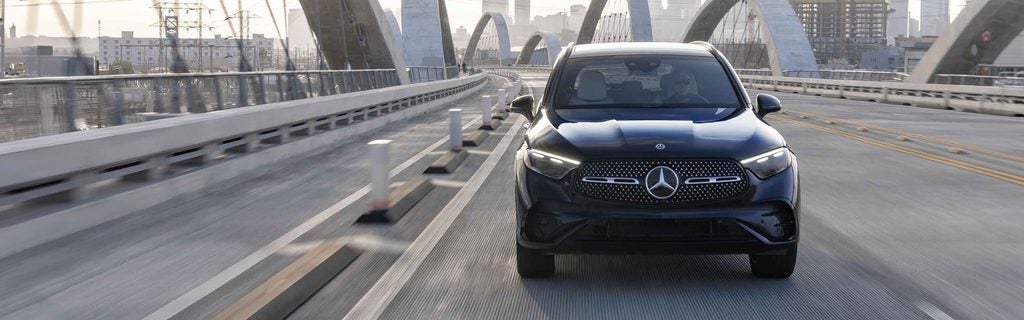 Mercedes-Benz GLC SUV driving across a modern city bridge.