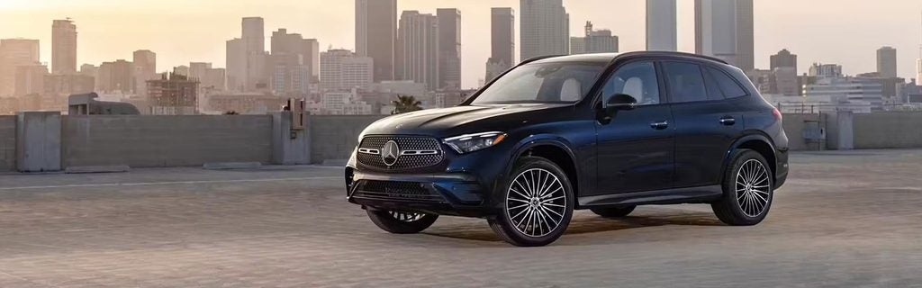 Dark blue Mercedes-Benz GLC SUV on a rooftop with a city skyline.