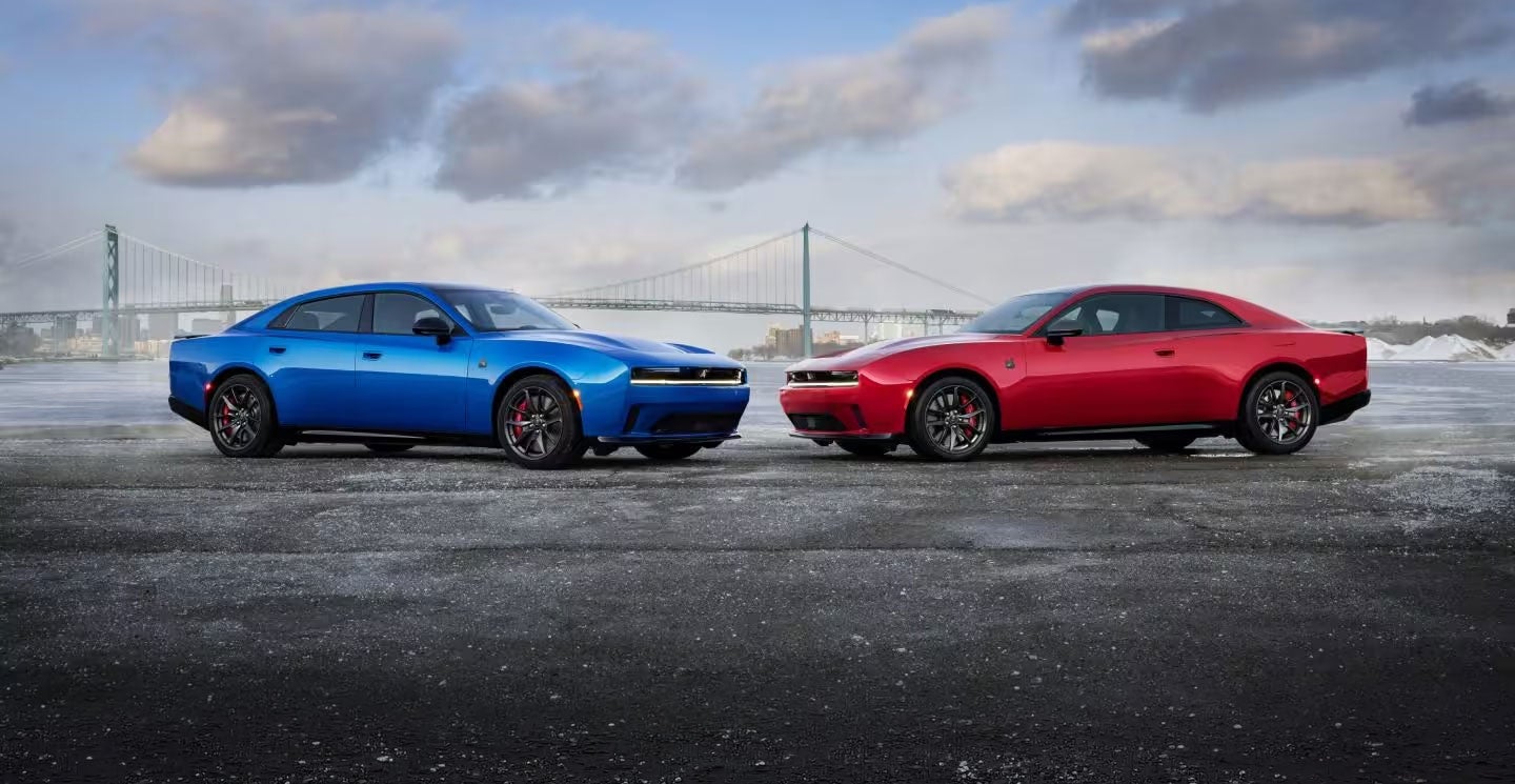 A blue four-door car and a red two-door car with black wheels face each other on an icy asphalt lot.