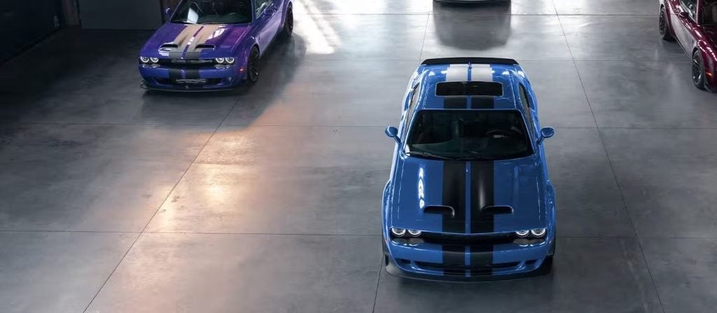 Aerial view of three Dodge Challenger cars in a garage: blue (center), purple (left), and maroon (right).