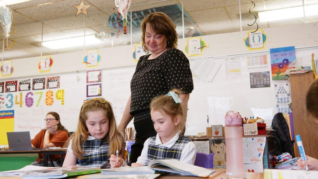 Teacher assisting two students during a classroom activity