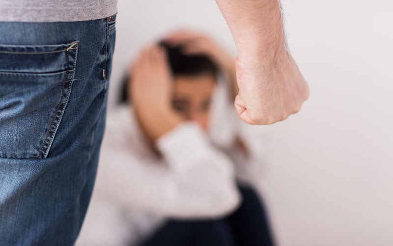 Aggressive hand gesture with person sitting in distress in background.