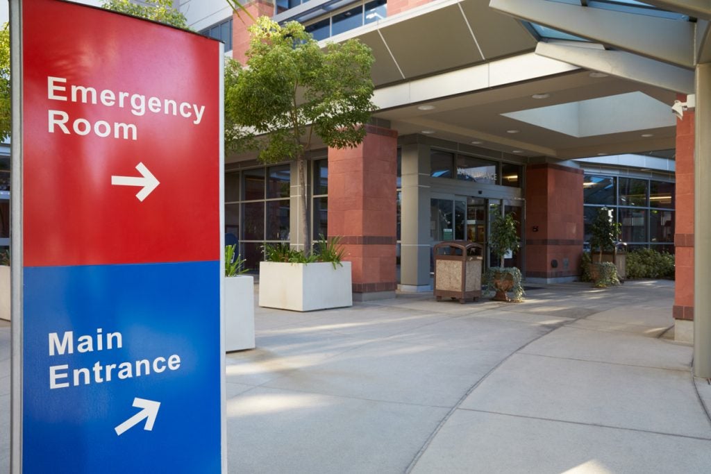Hospital sign pointing to the Emergency Room and Main Entrance outside a medical building