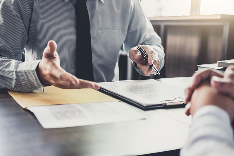 Business meeting with person reviewing documents and explaining contract across desk