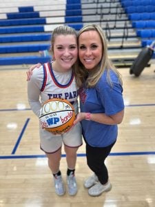 Mother and daughter smiling, hugging and holding a basket ball