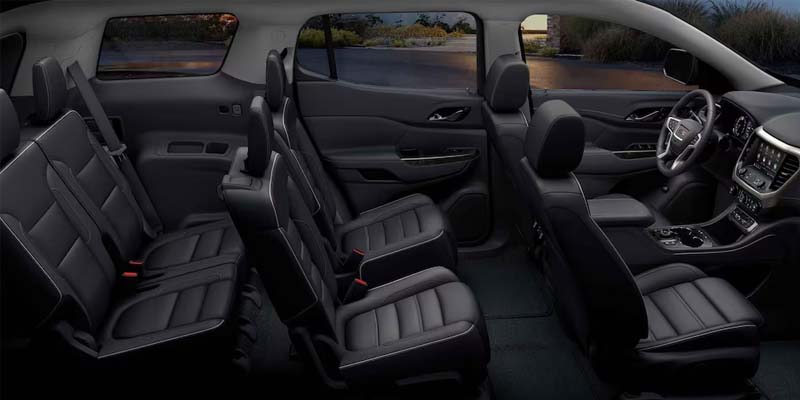 Car interior with three rows of black leather seats, including front, middle, and rear seating, along with a visible dashboard
