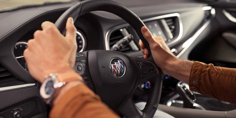 This image shows the interior of a Buick vehicle, focusing on the steering area and driving perspective.