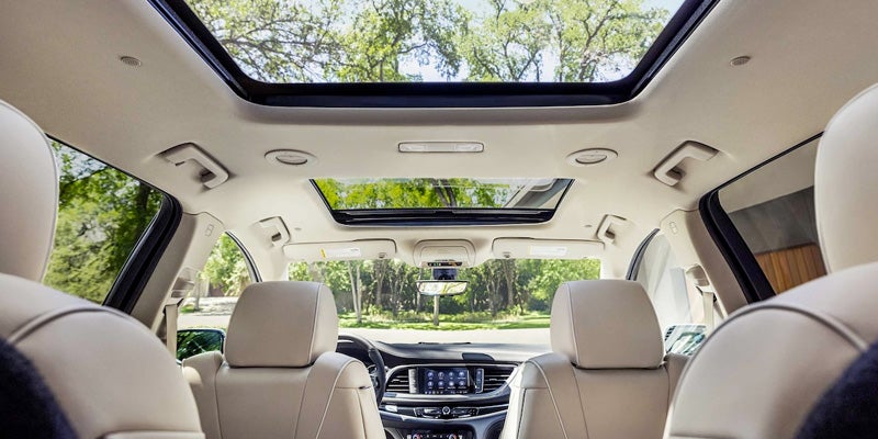 Interior view of a car featuring beige leather seats and a large panoramic sunroof, with a second glass panel above the rear seats.