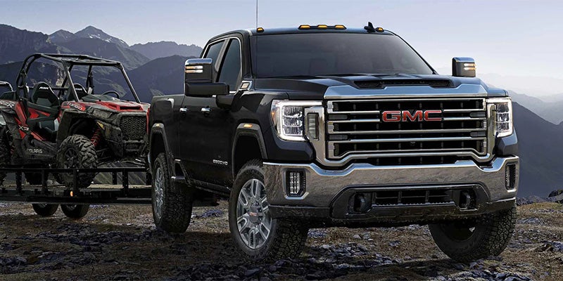 The truck is parked on rocky terrain in a mountainous landscape, suggesting off-road or rugged capability.