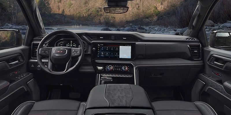 Interior view of a dark gray truck with a digital dashboard, large infotainment screen, and a wooded landscape.
