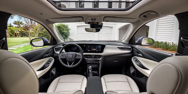 Front interior view of a modern SUV showing a light-colored cabin with two front seats, a central touchscreen dashboard, steering wheel