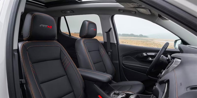 Car interior with black leather front seats featuring red stitching and AT4 logo on the headrests, a spacious cabin with center console