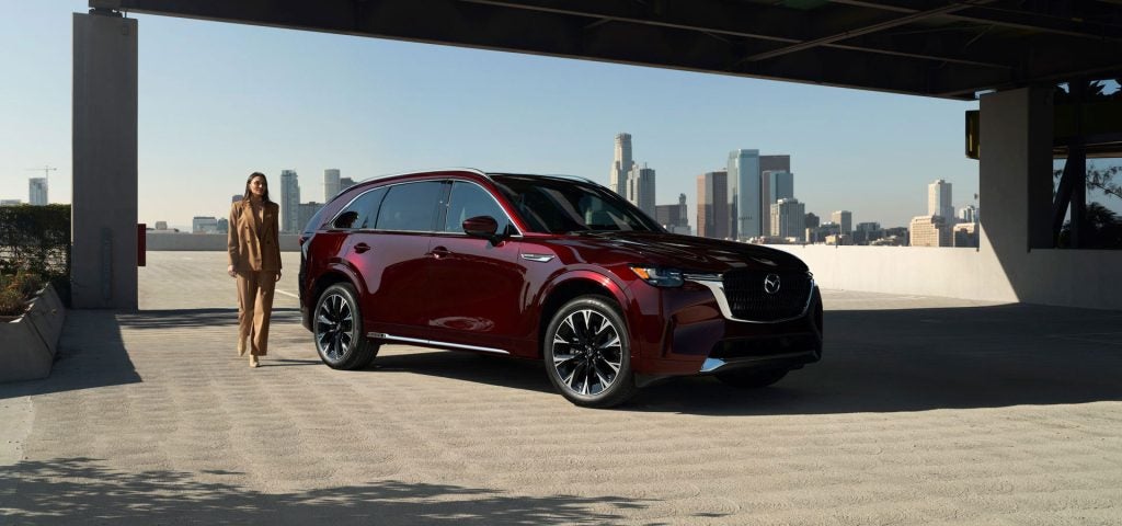 Dark red SUV parked in a modern open-air structure with a city skyline in the background