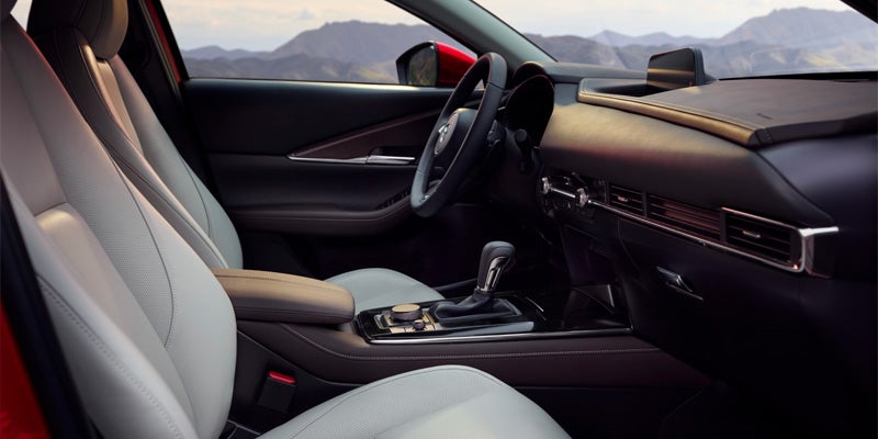 Premium Mazda interior featuring light-colored leather front seats, a driver-focused cockpit, center console controls