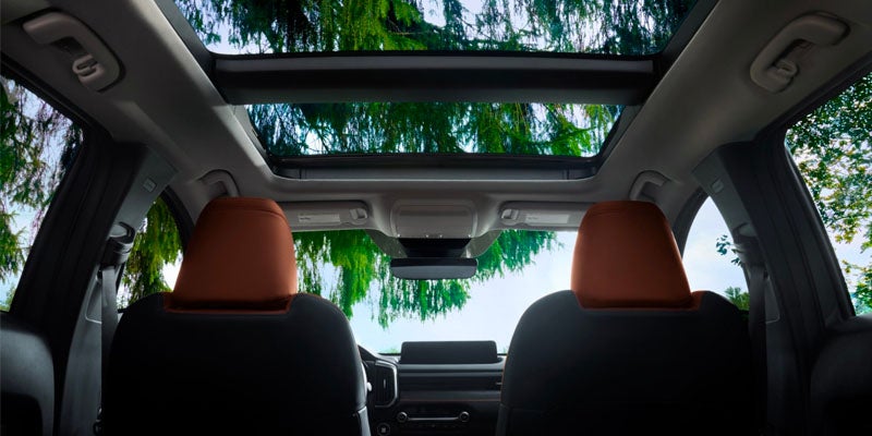 Interior view of a Mazda SUV featuring a large panoramic moonroof that spans above the front and rear seating areas.