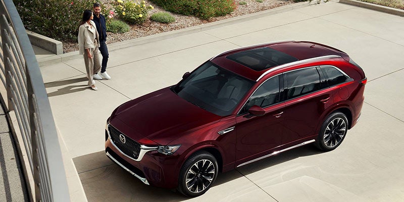 High-angle view of a dark red SUV parked in a modern outdoor plaza, highlighting its panoramic sunroof