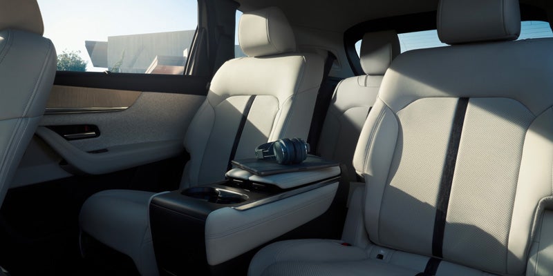 Rear passenger cabin of a Mazda SUV with light-colored leather seats, a fold-down center armrest with cup holders