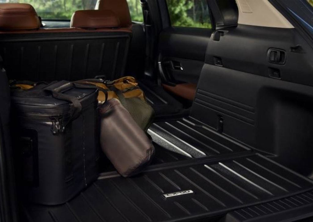 Mazda SUV cargo area with luggage and an all-weather cargo liner.
