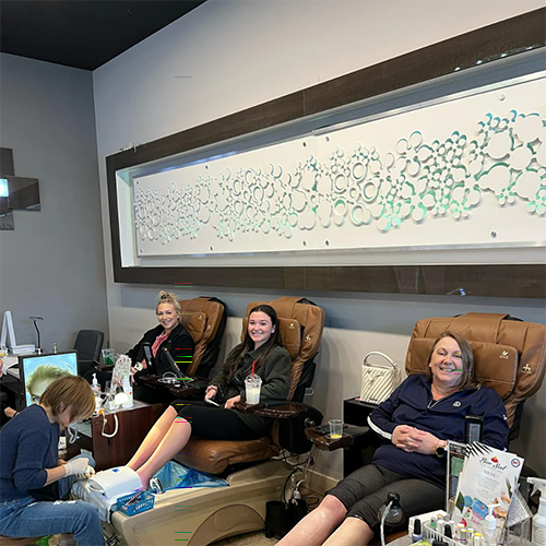 Employees enjoying pedicures and relaxing in salon massage chairs.