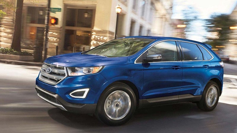 Blue 2017 Ford Edge SUV driving on a city street with motion blur, creating a sense of speed.