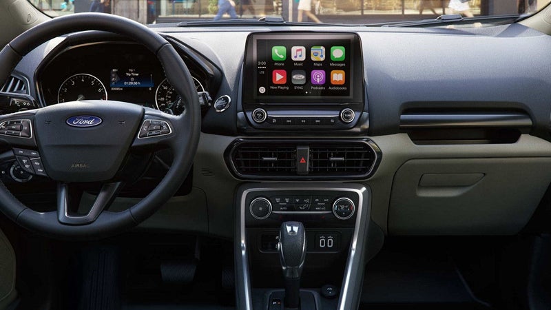 The interior dashboard of a Ford car, showing the steering wheel, digital display, infotainment screen, and gear shift.