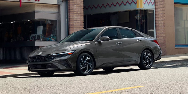Hyundai Elantra parked angled on a city street, with storefronts and brick buildings in the background.