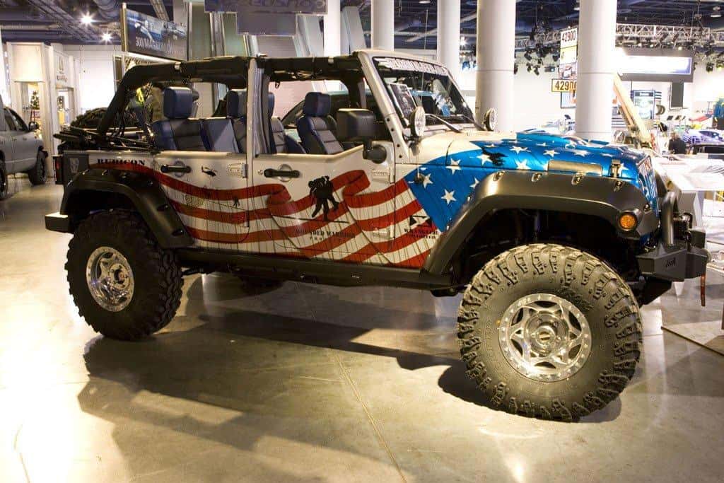 Jeep Wrangler Rubicon wrapped in an American flag design honoring wounded veterans, on display at an auto show