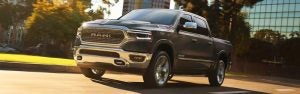 Silver 2019 Ram 1500 Limited driving past a glass building