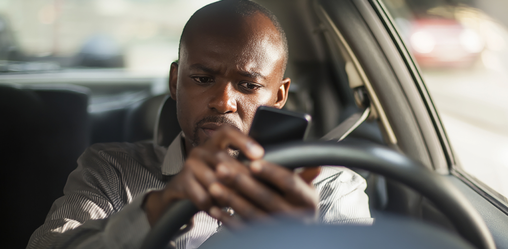 Man texting on smartphone while driving car, distracted driving risk