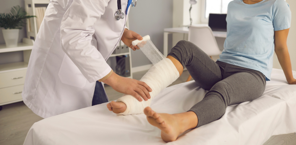 Doctor wrapping a patient’s bandaged leg in a medical clinic