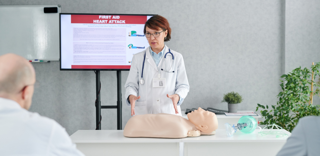 Doctor demonstrating CPR on a mannequin during a first aid training class on heart attack response