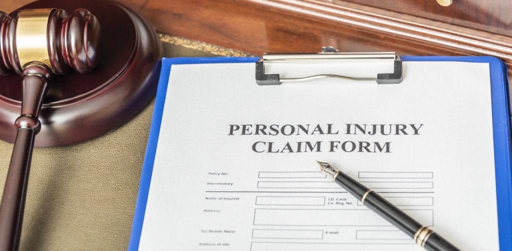 Personal injury claim form on clipboard with gavel and pen on desk