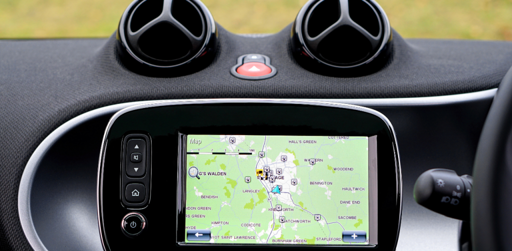 Car dashboard GPS displaying a map with routes and nearby towns marked