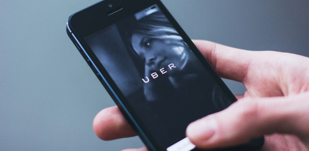 Hand holding a phone with the Uber app open, suggesting a safe ride alternative
