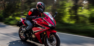Motorcyclist in helmet riding a red sport bike at speed on a forest road with motion blur background