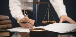 Justice scales in foreground with lawyer signing documents, symbolizing legal balance and personal injury case work