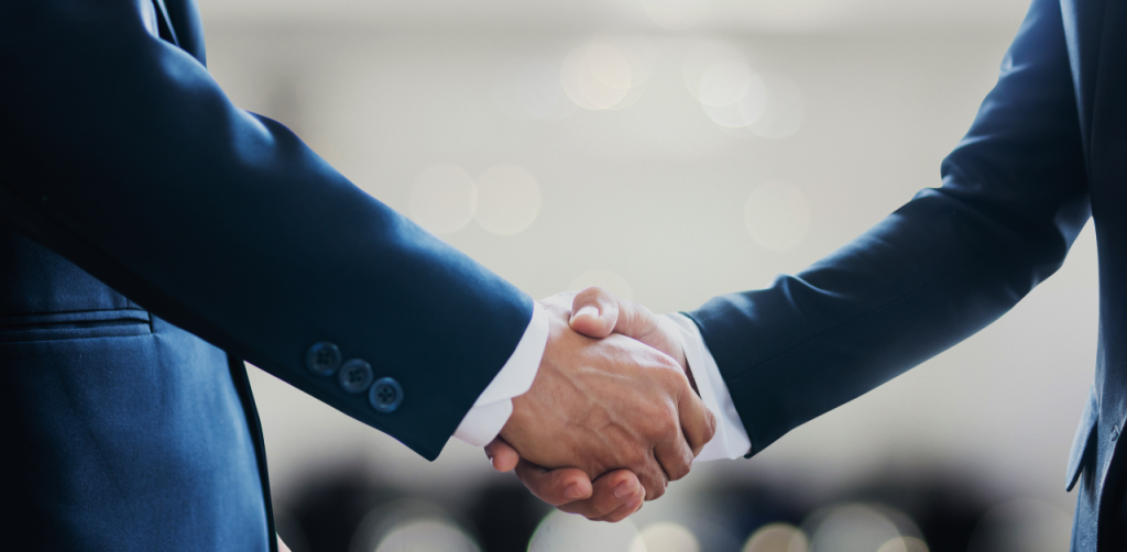 Two business professionals in suits shaking hands, symbolizing a successful legal agreement