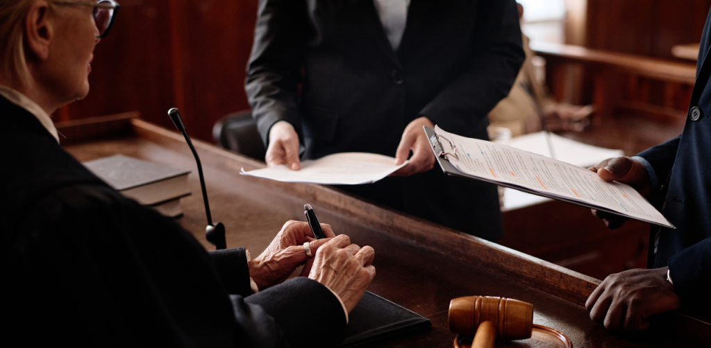 Judge in courtroom receiving legal documents from attorneys during a case hearing