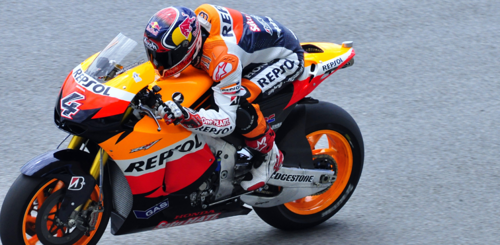 Motorcycle racer in full gear riding a Repsol Honda bike on a racetrack