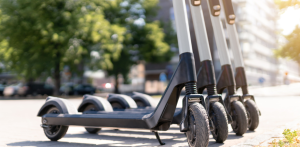 Row of electric scooters lined up on a sunny city sidewalk, ready for urban micromobility use