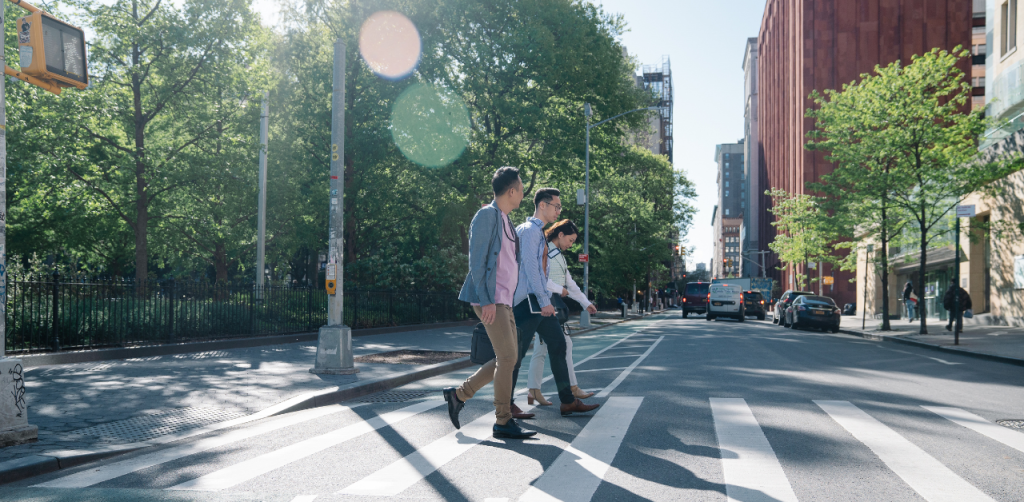People crossing a city street in daylight, highlighting urban crosswalks and pedestrian safety