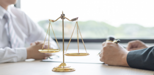 Scales of justice on desk between two professionals, symbolizing legal consultation or dispute resolution