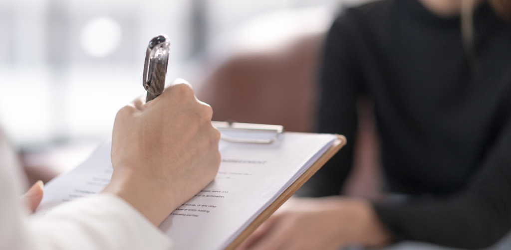 Close-up of a therapist writing notes on a clipboard during a counseling session