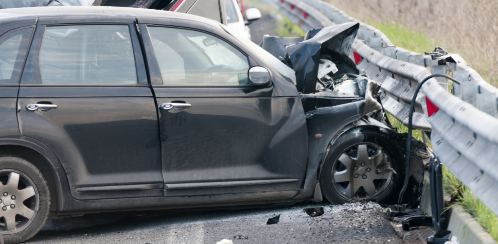 Badly damaged car on guardrail after a crash, showing severity of a car accident claim case
